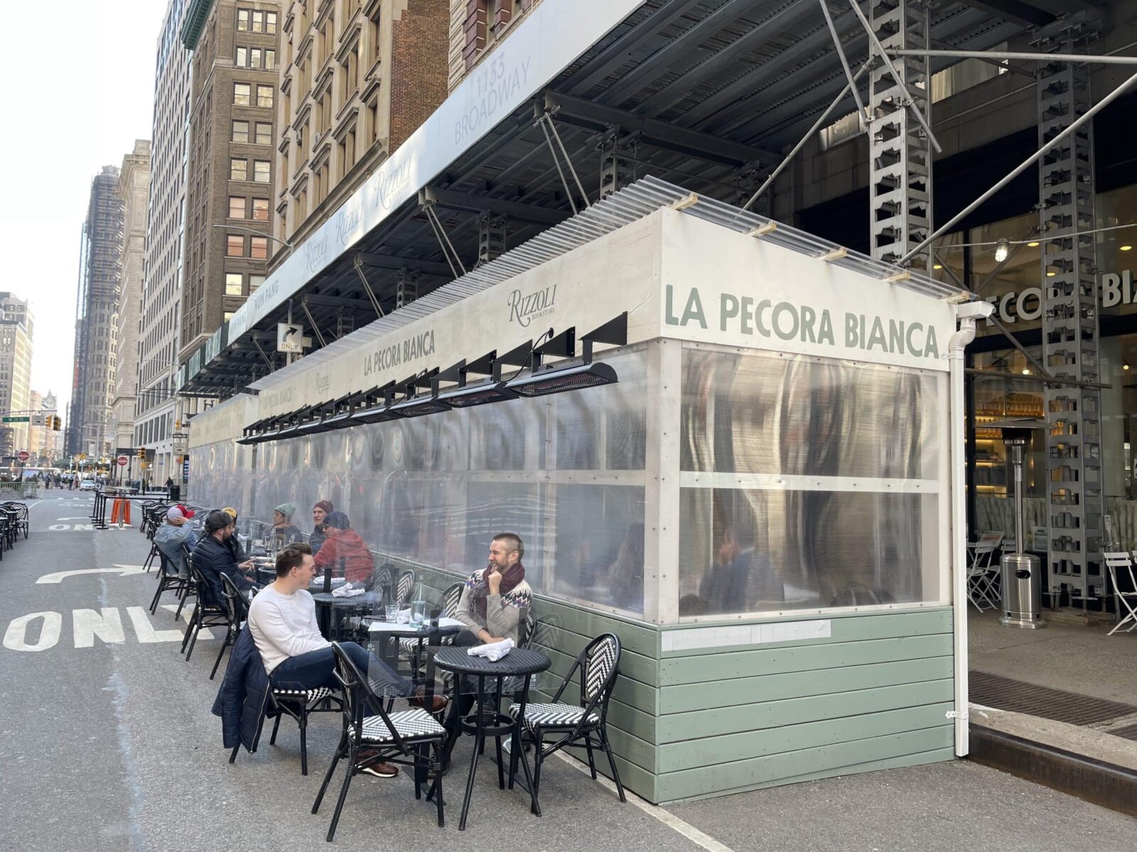 I posti a sedere del ristorante si estendono all'esterno sulla strada a New York con riscaldatori elettrici